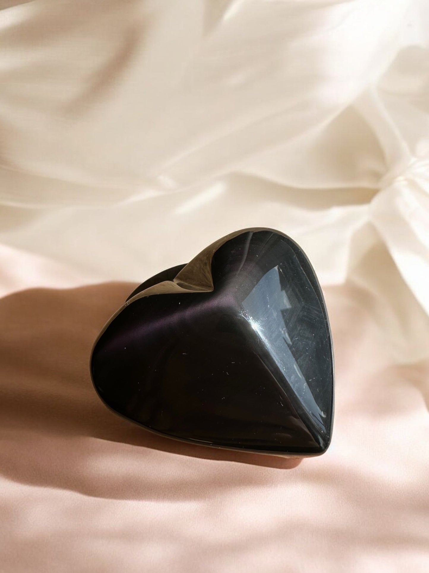 Rainbow obsidian crystal heart on a table