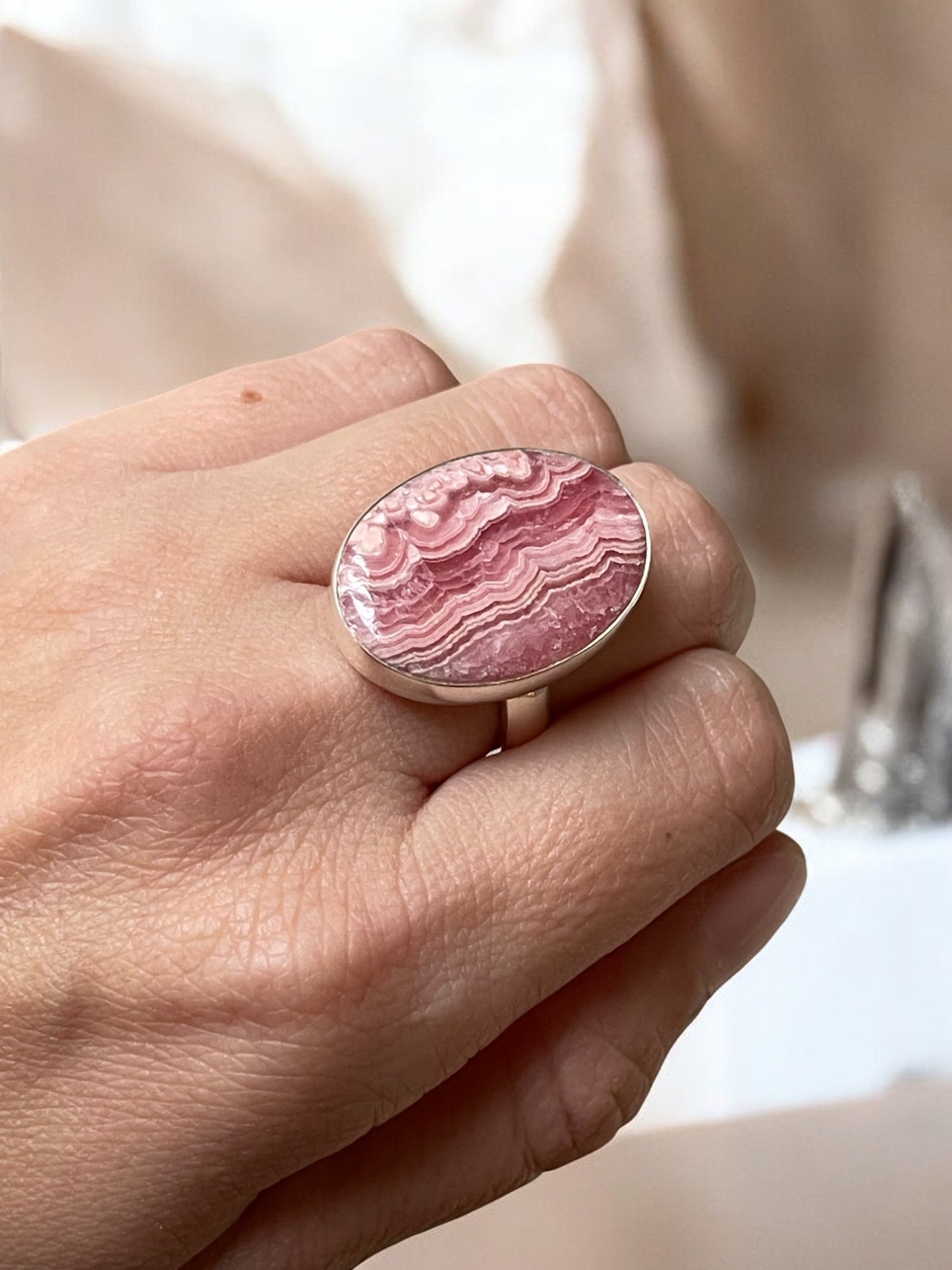 Rhodochrosite crystal ring on a finger