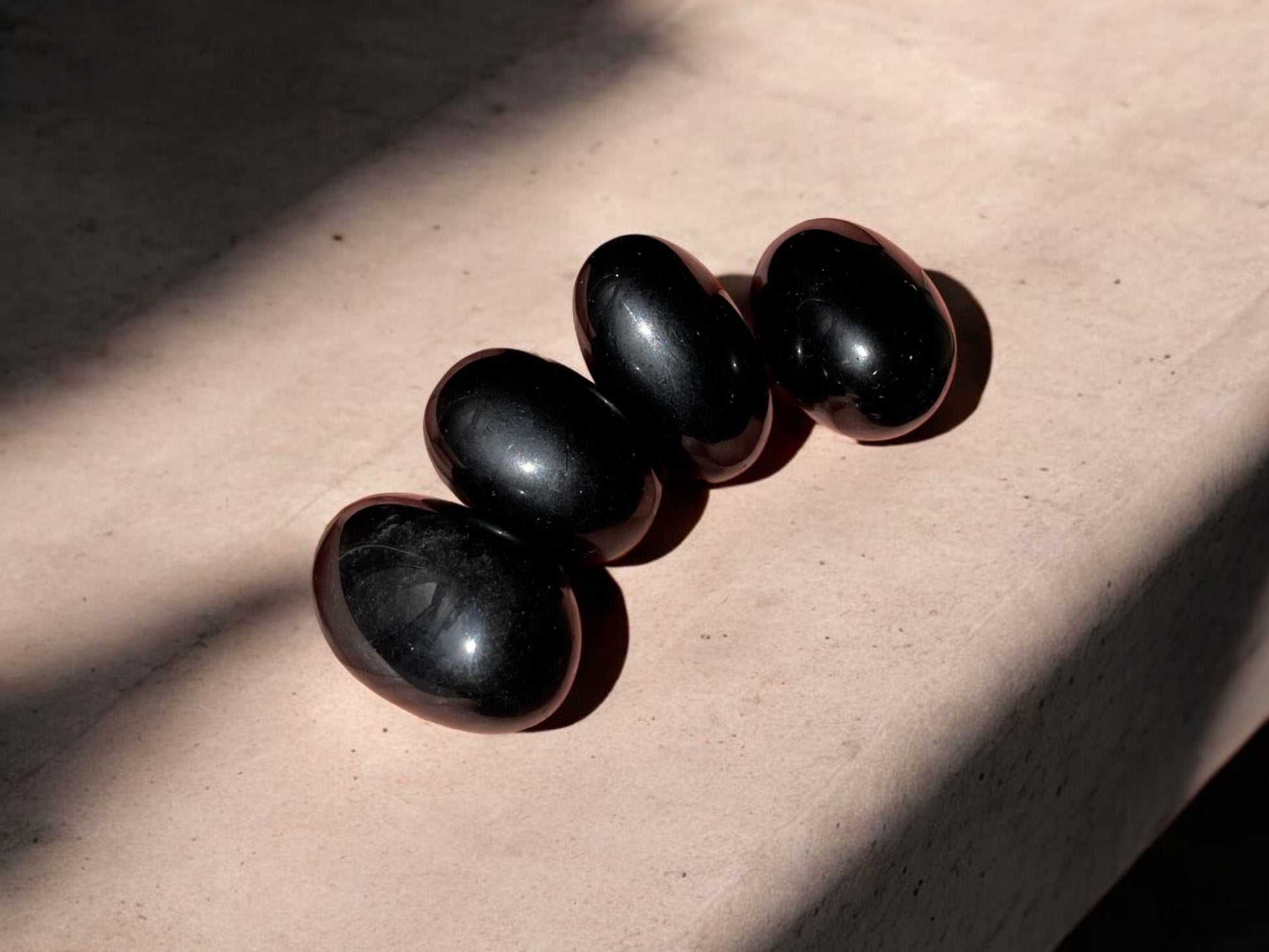 Black obsidian tumbled crystals on concrete